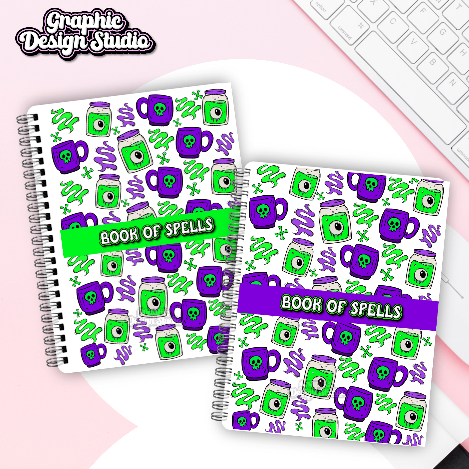 Two spiral-bound notebooks with 'Book of Spells' design on a pink surface with a keyboard.