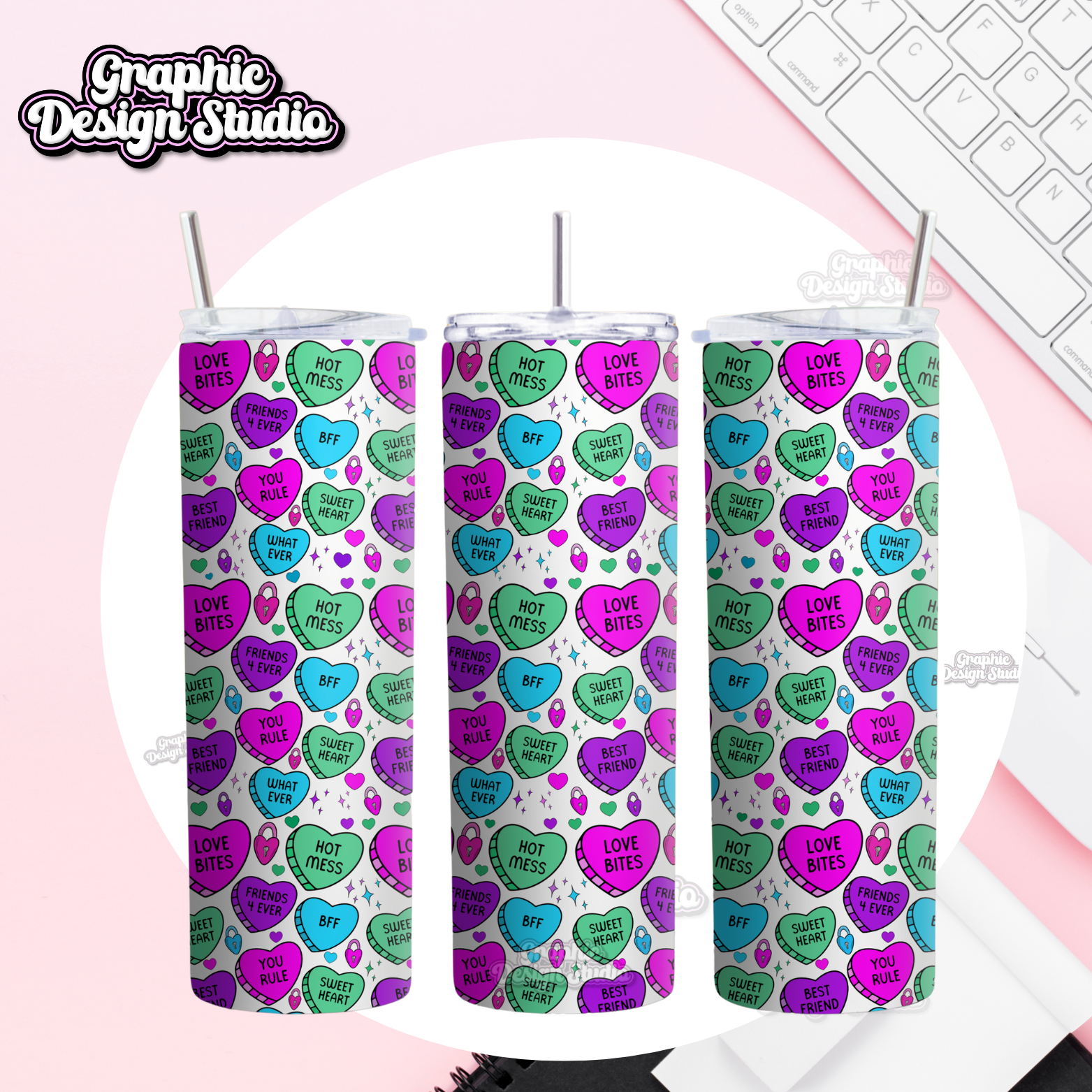 Three tumblers with colorful heart pattern on a pink surface with keyboard in the background
