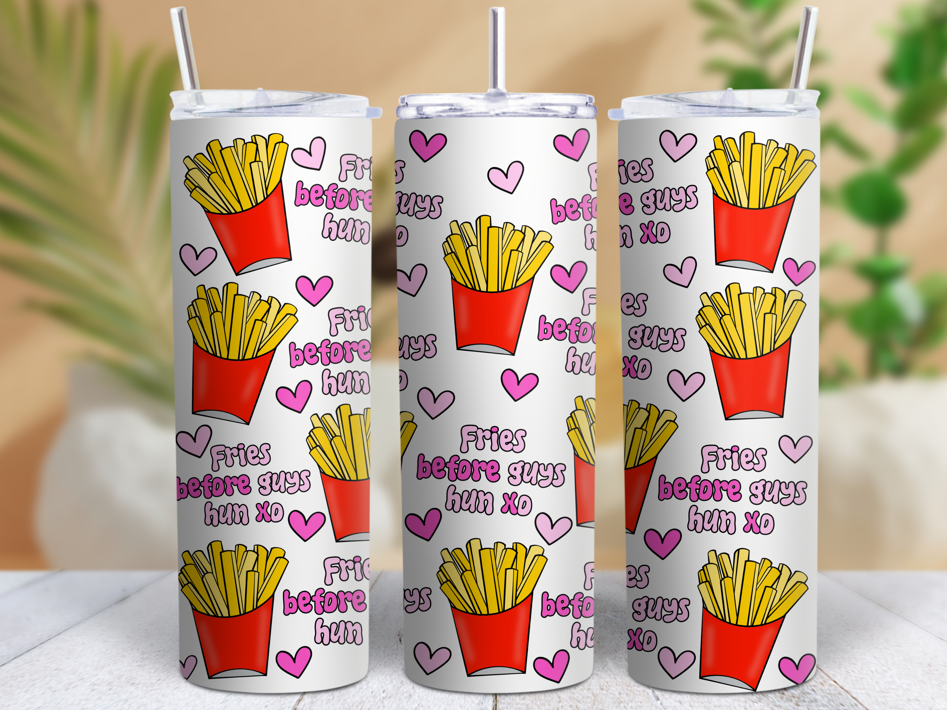 Three white tumblers with french fry design and text on a blurred background